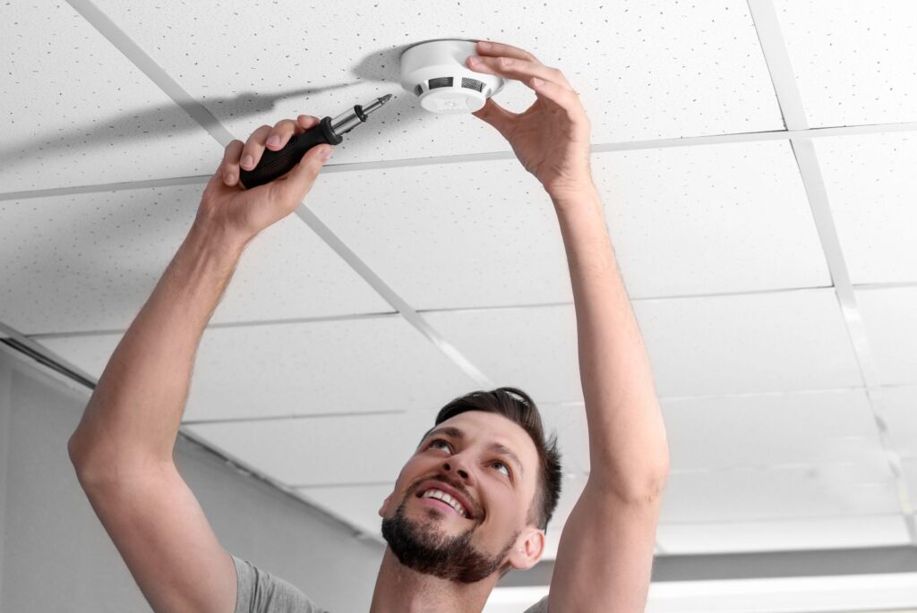 electrician installing a smoke alarm in ceiling