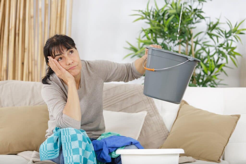 woman holding a bucket to catch water leak