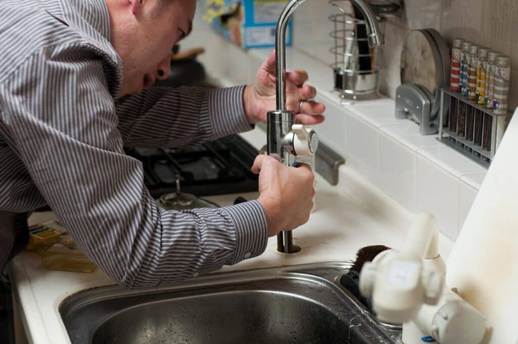 A plumber installing a new tap for a sink
